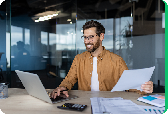 Glimlachende man die op een laptop werkt in een modern kantoor en energiecontracten online vergelijkt.